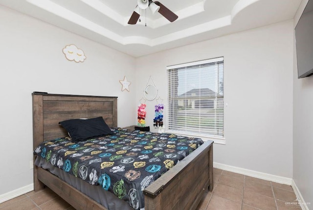 bedroom with a tray ceiling, tile patterned floors, baseboards, and ceiling fan