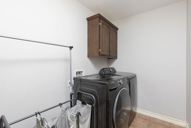 washroom featuring cabinet space, baseboards, light tile patterned floors, and separate washer and dryer