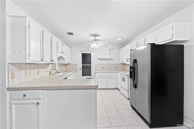 kitchen with tile countertops, backsplash, stainless steel refrigerator with ice dispenser, white cabinetry, and kitchen peninsula