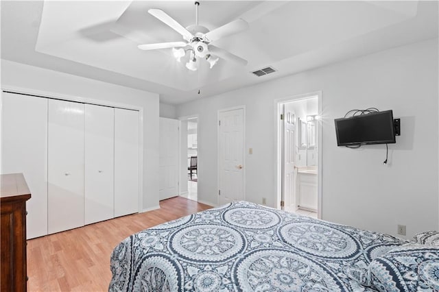 bedroom featuring a closet, ensuite bath, light hardwood / wood-style flooring, and ceiling fan