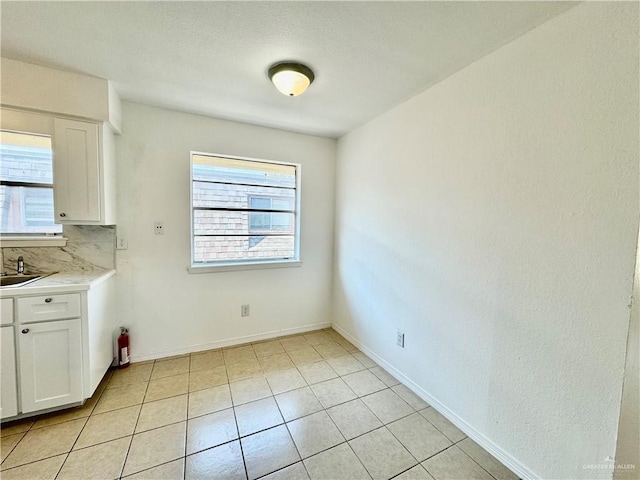 unfurnished dining area with sink, a wealth of natural light, and light tile patterned flooring