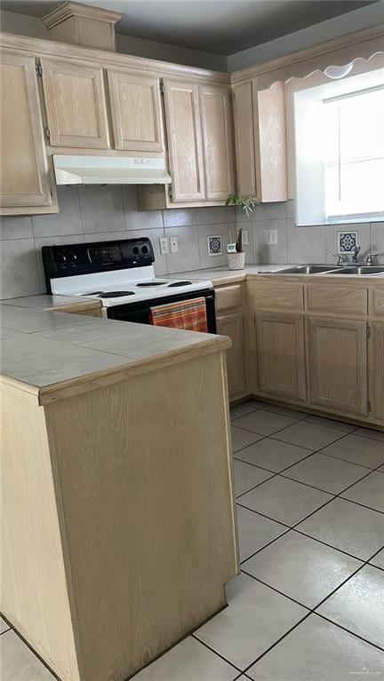 kitchen with backsplash, electric range, and light brown cabinetry