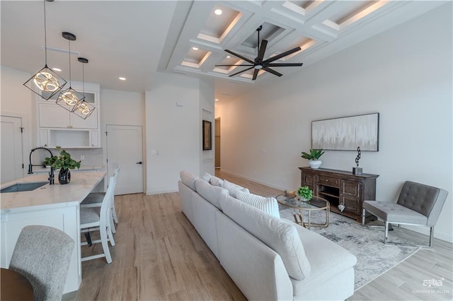 living area featuring recessed lighting, coffered ceiling, light wood finished floors, and a high ceiling