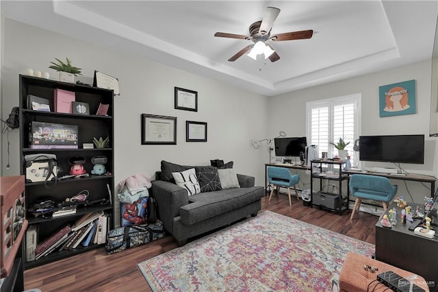 living room featuring a tray ceiling, dark hardwood / wood-style floors, and ceiling fan