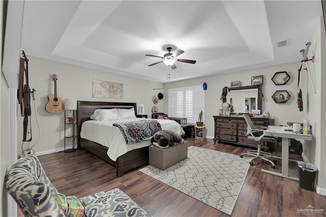 bedroom featuring a raised ceiling, ceiling fan, and dark wood-type flooring