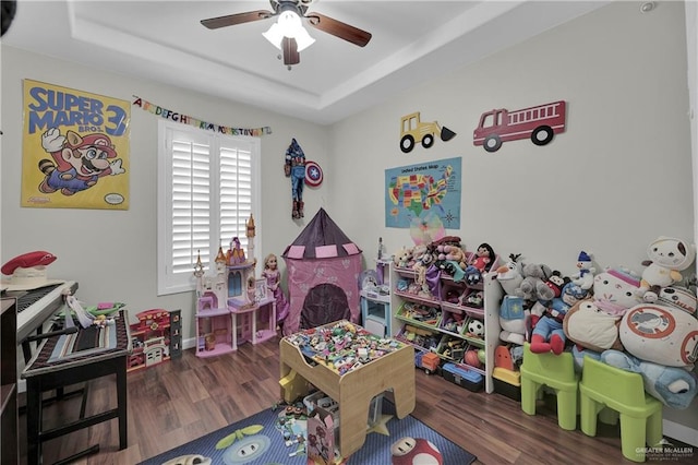 rec room with dark hardwood / wood-style floors, ceiling fan, and a tray ceiling