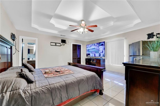 tiled bedroom with ensuite bathroom, a raised ceiling, and ceiling fan