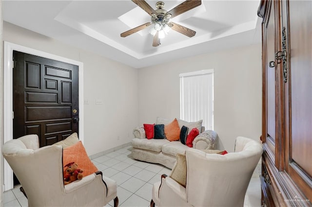 tiled living room featuring a raised ceiling and ceiling fan