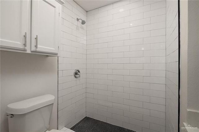 bathroom with a tile shower and toilet