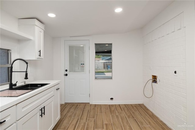 washroom with cabinets, brick wall, hookup for a washing machine, and sink