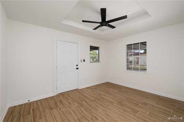 empty room featuring ceiling fan and a raised ceiling