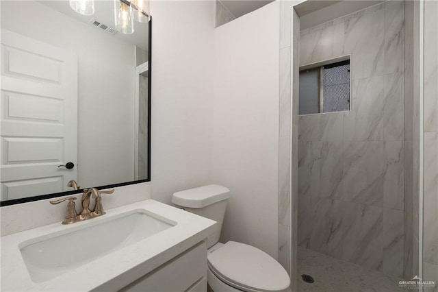 bathroom featuring vanity, toilet, and a tile shower