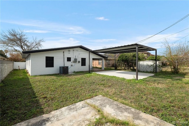 rear view of house with a patio, cooling unit, and a lawn