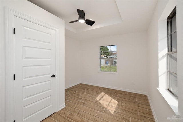 unfurnished room with ceiling fan and a tray ceiling