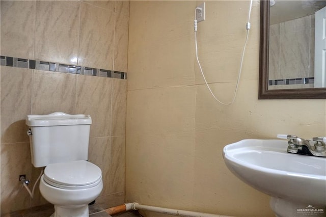 bathroom featuring tile walls, sink, and toilet