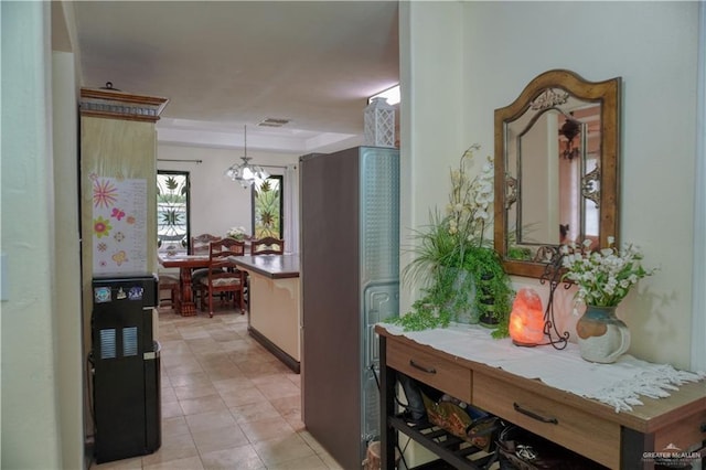 hall with light tile patterned floors and a notable chandelier