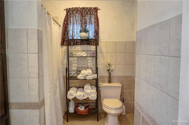 bathroom with tile patterned flooring, tile walls, and toilet