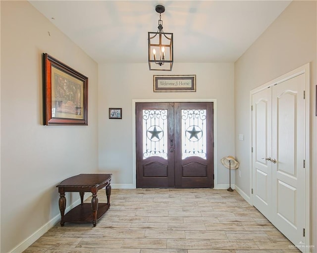 entrance foyer featuring a chandelier, light hardwood / wood-style floors, and french doors