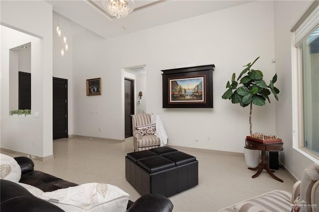 living area with a chandelier, a high ceiling, and baseboards