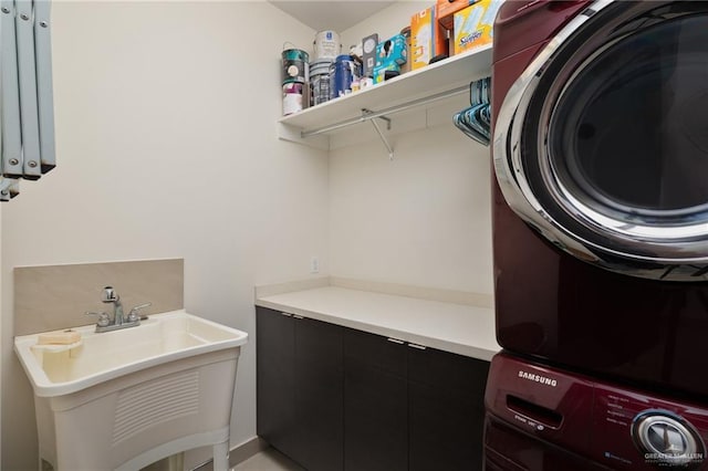 clothes washing area featuring a sink, cabinet space, and stacked washer / drying machine