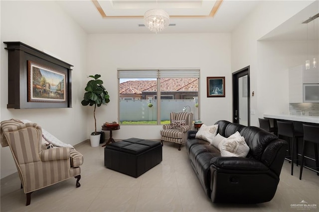 living room with light tile patterned floors, a raised ceiling, and a notable chandelier