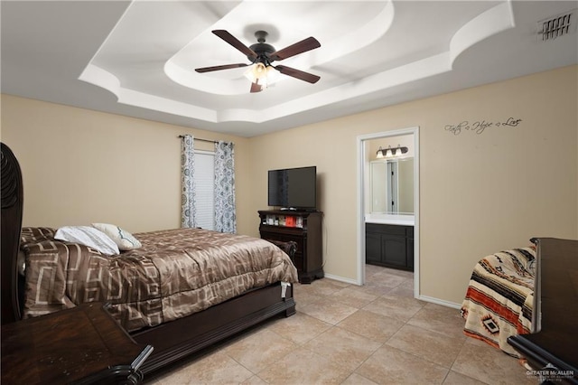 bedroom with connected bathroom, a tray ceiling, ceiling fan, and light tile patterned flooring