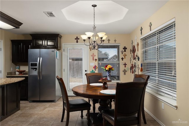dining room with light tile patterned flooring, visible vents, an inviting chandelier, and a raised ceiling