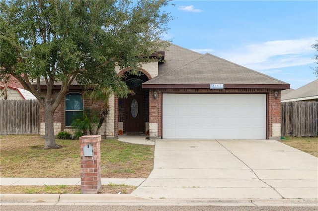 view of front of home with roof with shingles, concrete driveway, fence, and brick siding