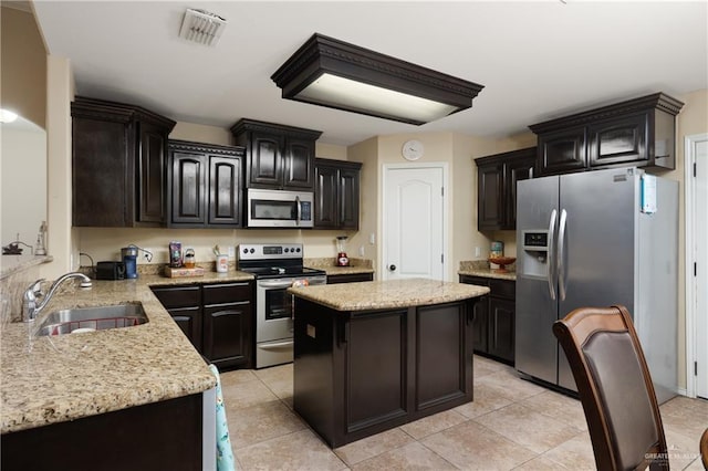 kitchen with dark brown cabinetry, sink, a center island, light tile patterned floors, and appliances with stainless steel finishes