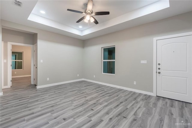 interior space with ceiling fan, light wood-type flooring, and a tray ceiling