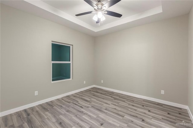 spare room featuring ceiling fan, light hardwood / wood-style floors, and a raised ceiling