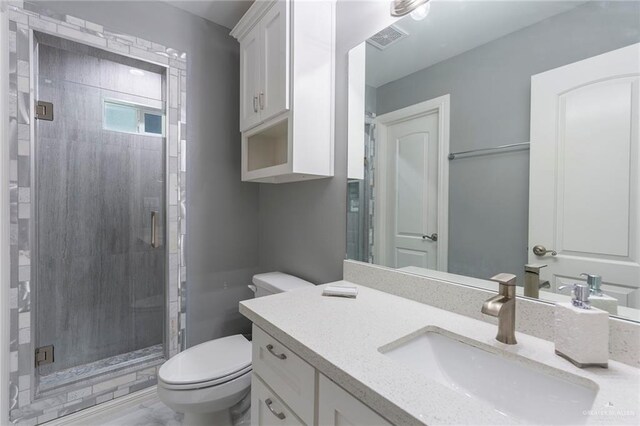 bathroom with vanity, toilet, and a shower with door