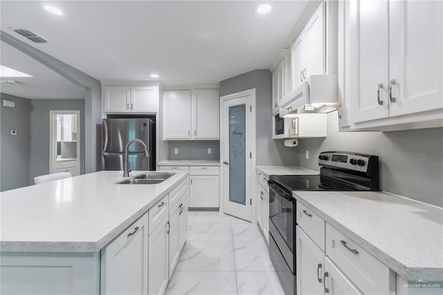 kitchen with stainless steel appliances, extractor fan, sink, white cabinetry, and an island with sink