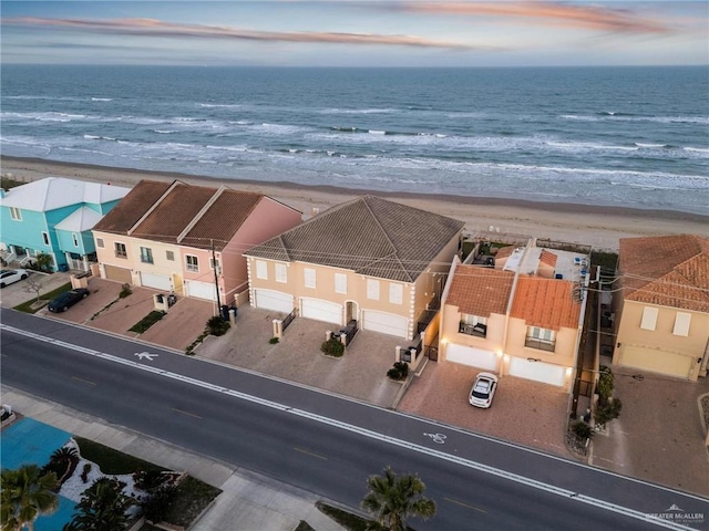 aerial view at dusk with a water view and a beach view