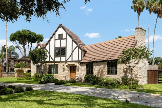707 N 15th St, Mcallen, TX 78501 - tudor house with stone siding, a front lawn, stucco siding, and a chimney