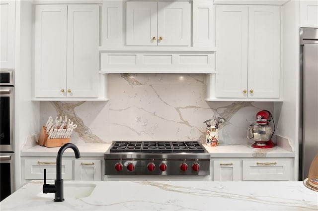 707 N 15th St, Mcallen, TX 78501 - kitchen featuring white cabinetry, backsplash, light stone counters, and appliances with stainless steel finishes