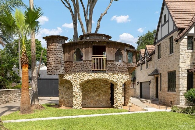 707 N 15th St, Mcallen, TX 78501 - view of front facade featuring a balcony, stone siding, a garage, and a front yard