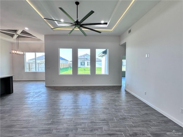 unfurnished living room featuring recessed lighting, dark wood finished floors, a raised ceiling, and ceiling fan with notable chandelier