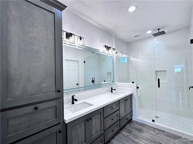 full bath featuring a sink, a stall shower, recessed lighting, and double vanity