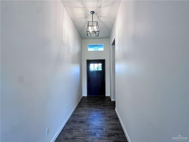 doorway to outside featuring baseboards, dark wood finished floors, and an inviting chandelier