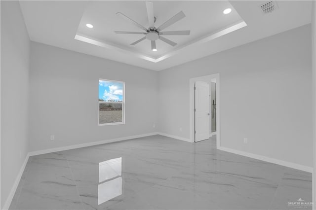 spare room featuring a tray ceiling and ceiling fan