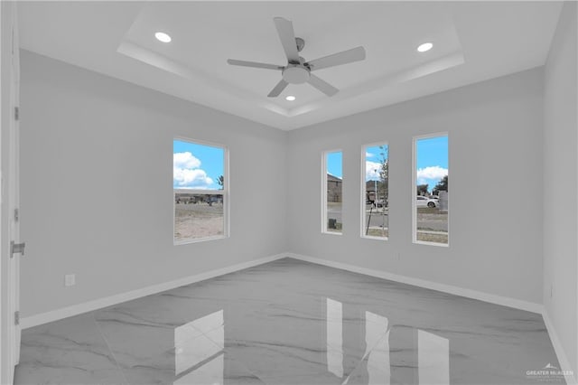 unfurnished room featuring a raised ceiling and ceiling fan