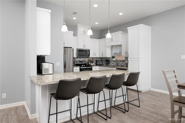 1012 Cooper Ln, San Juan, TX 78589 - kitchen with appliances with stainless steel finishes, a peninsula, backsplash, white cabinetry, and light stone countertops