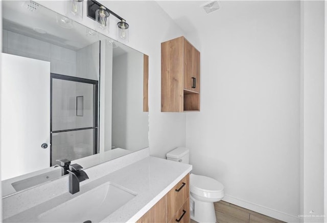 bathroom with a stall shower, baseboards, visible vents, toilet, and vanity