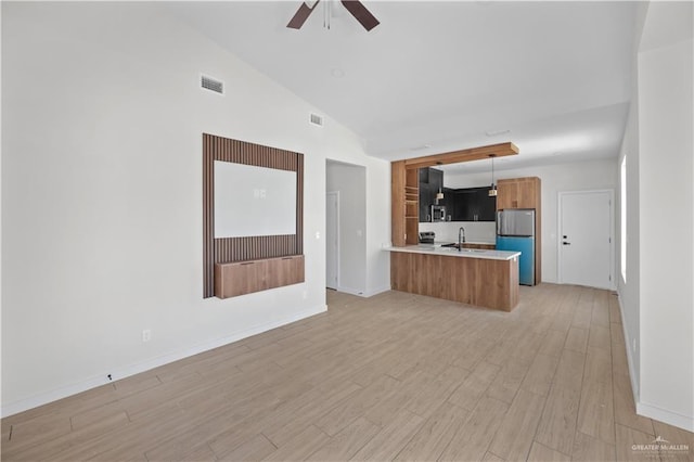 unfurnished living room featuring light wood-style flooring, visible vents, ceiling fan, and a sink