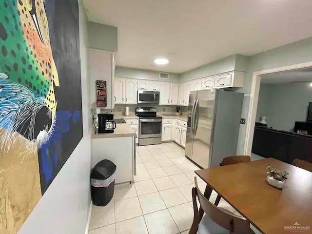 kitchen featuring white cabinets, stainless steel appliances, and light tile patterned flooring