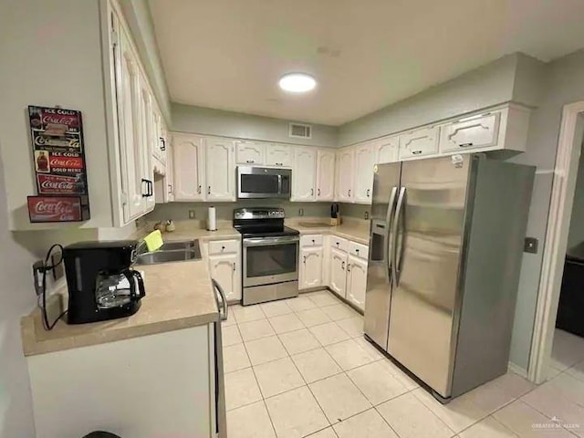 kitchen featuring white cabinets, stainless steel appliances, light tile patterned flooring, and sink