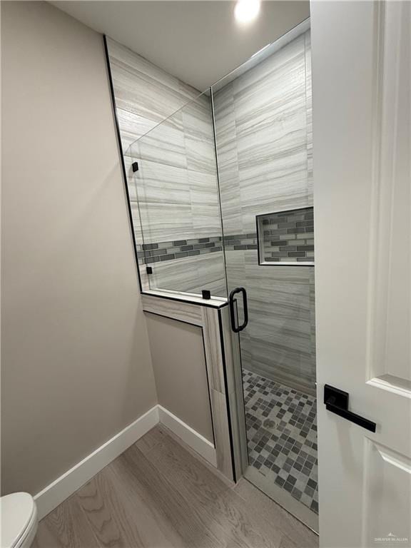 bathroom with toilet, hardwood / wood-style floors, and a shower with shower door