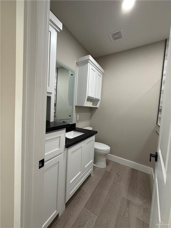 bathroom featuring vanity, hardwood / wood-style flooring, and toilet