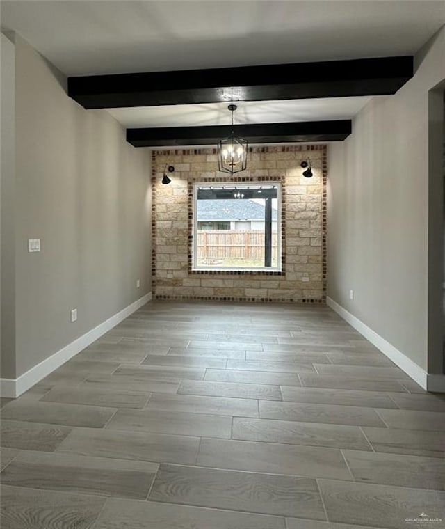 empty room featuring a notable chandelier and beam ceiling